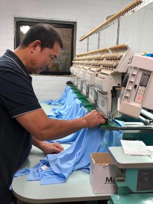 TIG employee embroidering shirt